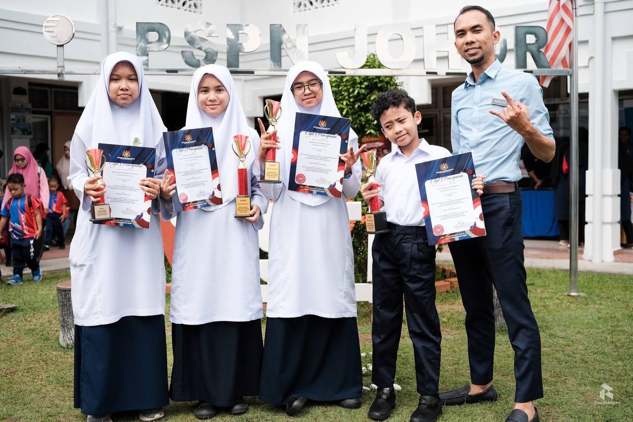 Izuan and BPNTV students holding certificates in the school grounds